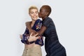 Photo of joyful ladies kissing and embracing togetherness, being of different of races, dressed in casual jumpers, isolated over