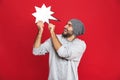 Photo of joyful man smiling and holding blank idea bubble isolated over red background Royalty Free Stock Photo