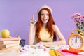 Photo of joyful student girl pointing finger upward sitting at desk with books Royalty Free Stock Photo