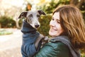 Photo of joyful woman with dog, feels fun, carries her lovely Italian Greyhound puppy, expresses affection, have good relationship Royalty Free Stock Photo