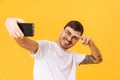 Photo of joyful young man taking selfie and pointing fingers