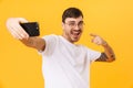 Photo of joyful young man taking selfie and pointing fingers