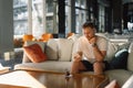 Young happy man using mobile phone in hotel lobby.