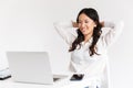 Photo of joyous chinese businesswoman with long dark hair sitting in office and working with documents and laptop, isolated over Royalty Free Stock Photo