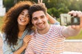 Photo of joyous couple man and woman taking selfie on mobile phone while sitting together on scooter Royalty Free Stock Photo