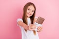 Photo of kind blond small girl give chocolate wear white t-shirt isolated on pink color background