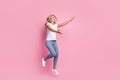 Photo of lady jump stretch hands catch look empty space wear white t-shirt jeans shoes isolated pink color background Royalty Free Stock Photo