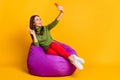 Photo of lady sit bean bag hold telephone take selfies show v-sign wear sweater pants shoes isolated yellow color