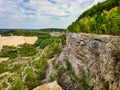 Photo landscape limestone quarry with trees that grow on the slope and below, a mountain of sand and a steep cliff with a cloudy Royalty Free Stock Photo