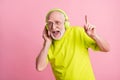 Photo of laughing optimistic old man listen music dance wear headphones spectacles green color clothes isolated on pink Royalty Free Stock Photo