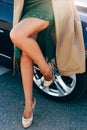 Photo of legs of woman in dress and raincoat close-up standing by car Royalty Free Stock Photo