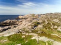 Photo of Lindesnes beacon in summer, South Norway. Aerial shot. Rocky sea coast and blue sky. Royalty Free Stock Photo