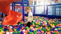 Photo of little boy playing in the pool full of colroful plastic balls. Toddler having fun on playground in shopping Royalty Free Stock Photo