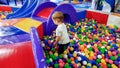 Photo of little boy playing in the pool full of colroful plastic balls. Toddler having fun on playground in shopping Royalty Free Stock Photo