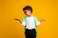 Photo of little funny schoolkid look arms hold empty space vs scales offer isolated on yellow color background