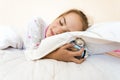 Photo of little girl sleeping and holding alarm clock under pill Royalty Free Stock Photo