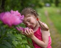 A photo of a little girl smelling big bright flowers with her eyes closed Royalty Free Stock Photo