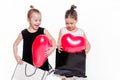 2 little girls with elegant dresses hold large bags with heart-shaped balloons inside Royalty Free Stock Photo