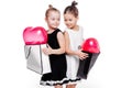 2 little girls with elegant dresses hold large bags with heart-shaped balloons inside Royalty Free Stock Photo