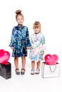 2 little girls with elegant dresses hold large bags with heart-shaped balloons inside Royalty Free Stock Photo
