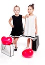 2 little girls with elegant dresses stay next to large bags with heart-shaped balloons inside Royalty Free Stock Photo