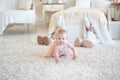 little happy girl in pink dress crawling and two toy rabbits behind her