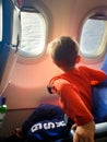 Image of little toddler boy sitting in airplane and looking out of the window Royalty Free Stock Photo