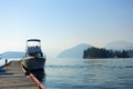 A photo of a lone bayliner power boat tied up to a dock, with the beautiful ocean and islands covered in forests in the background Royalty Free Stock Photo