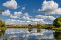 Photo of a lonely wooden house on the lake, which reflects summer clouds against the backdrop of chalk hills Royalty Free Stock Photo