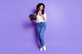 Photo of lovely lady hold box laugh hand chest wear hat white shirt jeans footwear isolated purple color background Royalty Free Stock Photo