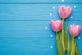 Photo of lovely pastel pink tulips on green stems with white glowing confetti in shape of hearts around lying on bright blue table