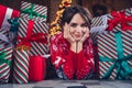 Photo of lovely young lady lying floor hands cheeks gift pile dressed stylish red sweater christmas tree decorated