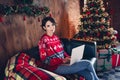 Photo of lovely young lady sitting sofa working netbook dressed stylish red sweater christmas tree decorated interior Royalty Free Stock Photo