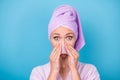 Photo of lovely young woman hands hold pink napkin nose wear purple towel turban bath robe isolated blue color Royalty Free Stock Photo