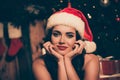 Photo of lovely young woman palms face look camera smile dream tease wear santa xmas headwear indoors Royalty Free Stock Photo