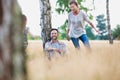 Loving mother plays with her daughter in the woods whilst her husband looks at the camera