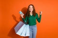 Photo of lucky funky lady dressed green shirt rising fists holding bargains chatting device isolated orange color