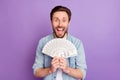 Photo of lucky funny young man wear jeans shirt holding arms hands money stack open mouth isolated violet color