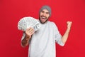 Photo of lucky guy rejoicing and holding cash money isolated over red background