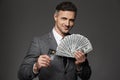 Photo of lucky guy 30s in business suit demonstrating money prize in dollar bills and credit card, isolated over gray background