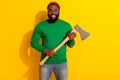 Photo of lumberjack man hold sharp axe wear red beanie green pullover isolated yellow color background Royalty Free Stock Photo