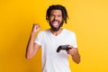 Photo of mad black guy hold joystick joystick open mouth raise arm fist wear white t-shirt isolated yellow color