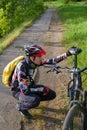 Photo of male cyclist wearing helmet next to bicycle on road in woods d Royalty Free Stock Photo