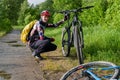 Photo of male cyclist wearing helmet next to bicycle on road in woods d