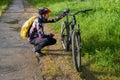 Photo of male cyclist wearing helmet next to bicycle on road in woods d Royalty Free Stock Photo