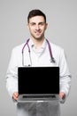 Photo of male doctor, smiling to camera and holding a laptop computer for the blank screen to add your own image of message on a w
