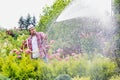 Photo of male gardener watering plants in garden shop