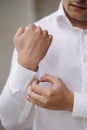 Photo of man fastens the cufflink on the shirt sleeve. Grooms morning on wedding. Close-up