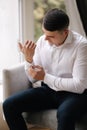 Photo of man fastens the cufflink on the shirt sleeve. Grooms morning on wedding