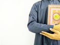 Photo of man holding a Koran ready for Ramadan. Arabic on the cover is translated as the Qur`an
